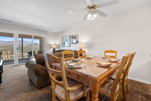 A dining area with a wooden table set for four, surrounded by wooden chairs with cushioned seats. A ceiling fan is visible above the table. - Las Palmas 326, Resort pool and clubhouse, Private balcony (Saint George)