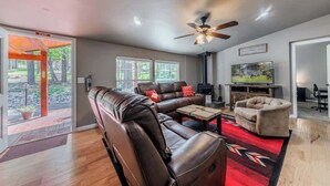 A living room with a leather sofa, a coffee table, a TV, and a fireplace. - Horseshoe Canyon | Cozy 3BR Cabin • Pet Friendly (Ruidoso)