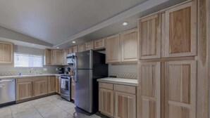 A modern kitchen with wooden cabinets, stainless steel appliances, and a tiled floor. - Horseshoe Canyon | Cozy 3BR Cabin • Pet Friendly (Ruidoso)