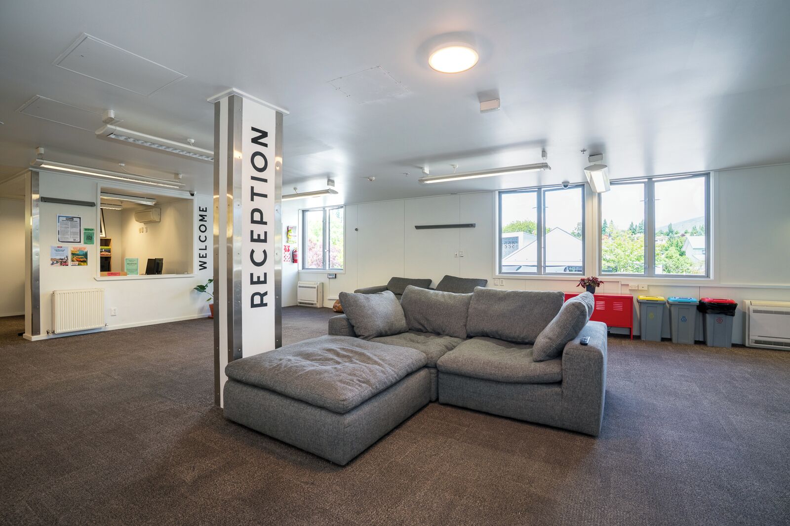A reception area with a grey sectional sofa, a reception desk, and a 'WELCOME' sign.