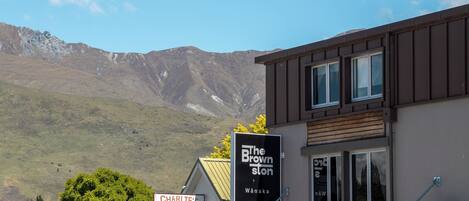 Un edificio con insegne per "The Brown Ston" e "Charlie’s Deli", sullo sfondo montagne.
