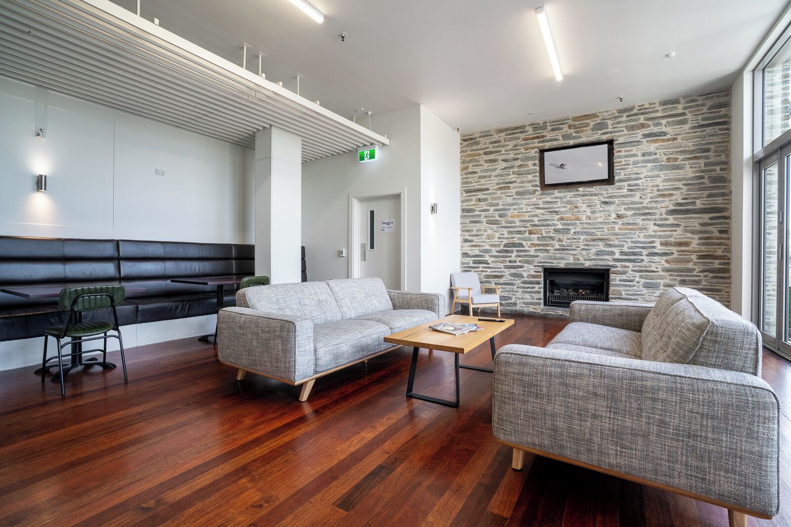 A modern lounge area with a stone wall, a fireplace, and a seating arrangement including a sofa and chairs.
