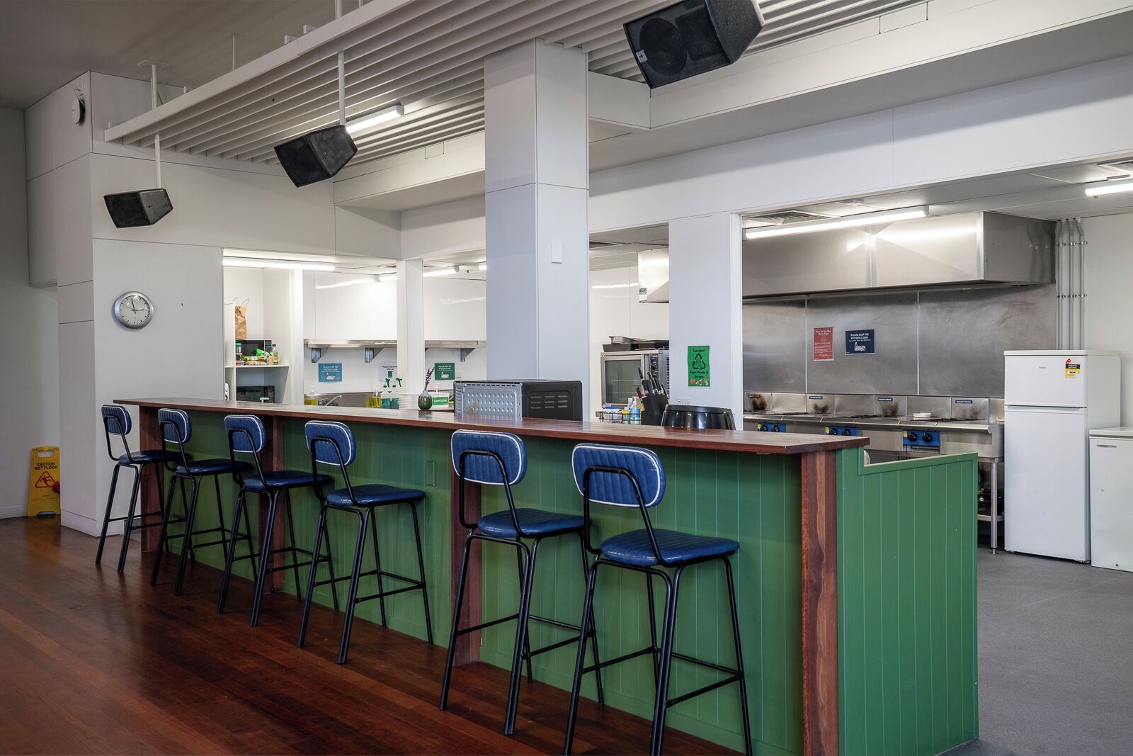 Amplia cocina con una isla central, taburetes de bar y un reloj en la pared.