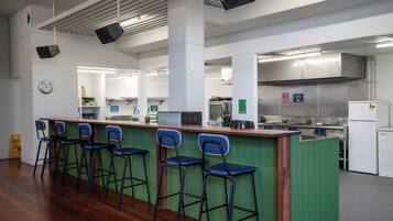 Amplia cocina con una isla central, taburetes de bar y un reloj en la pared.