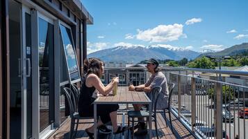 Una pareja cenando en una terraza de madera con vista a la montaña.