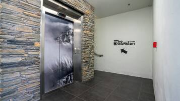 An elevator with a stone wall and a sign for "The Brownston".