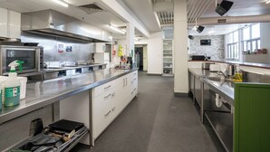 A modern kitchen with stainless steel appliances, a central island, and a view of the dining area. - The Brownston Hostel (Wanaka)