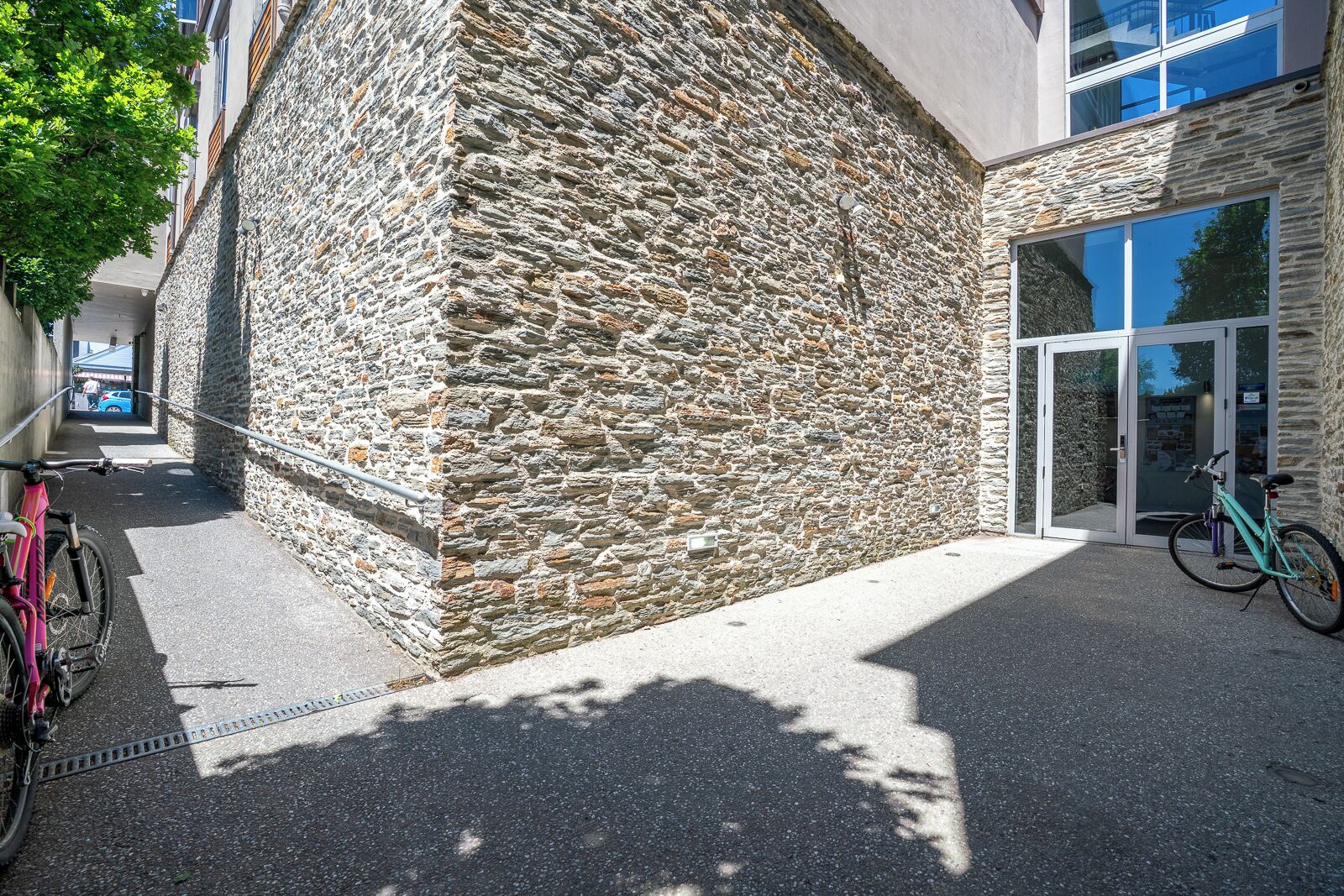 Un edificio de piedra con una entrada de vidrio moderna y bicicletas estacionadas afuera.