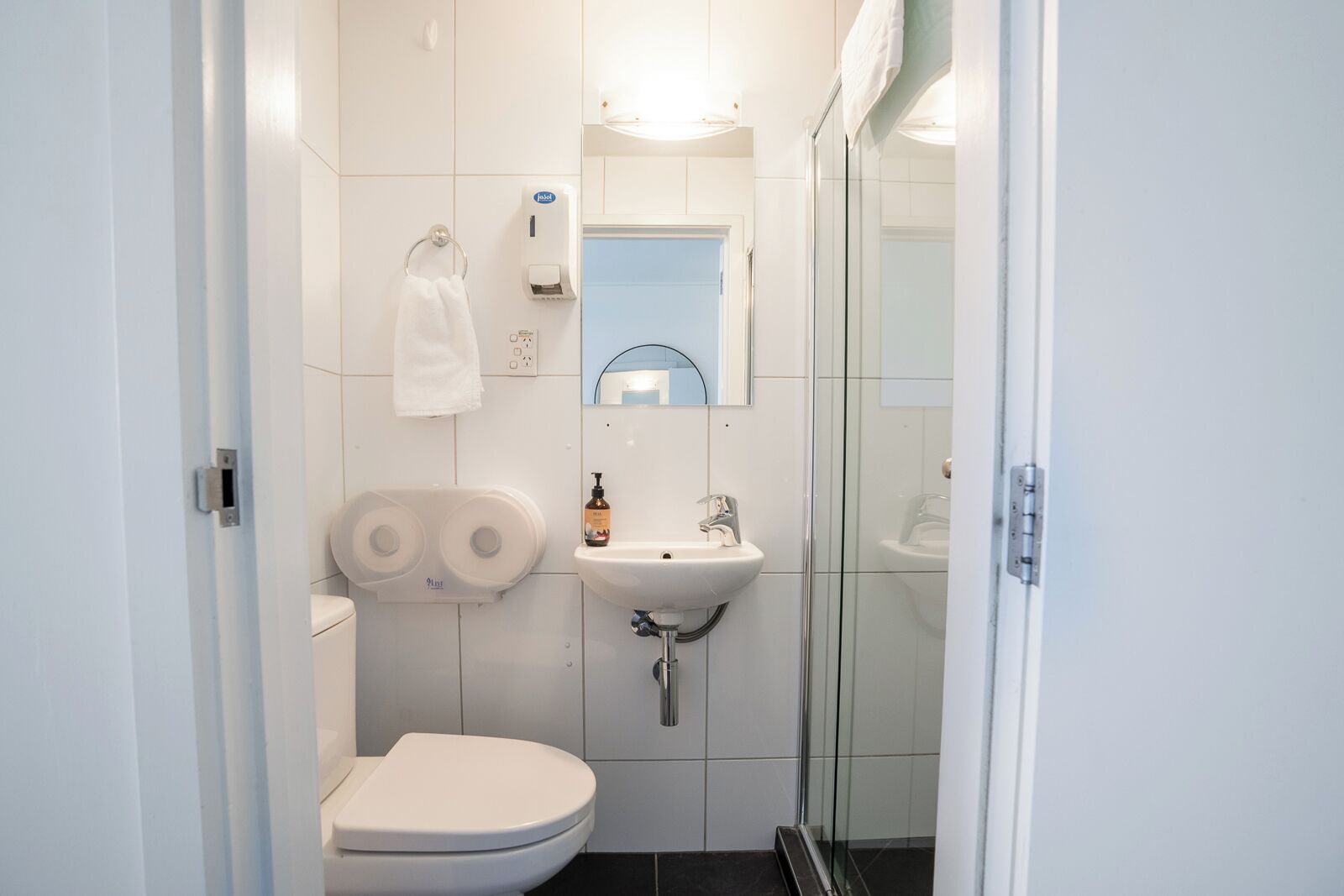 Un baño moderno con inodoro, lavamanos y cabina de ducha de vidrio.