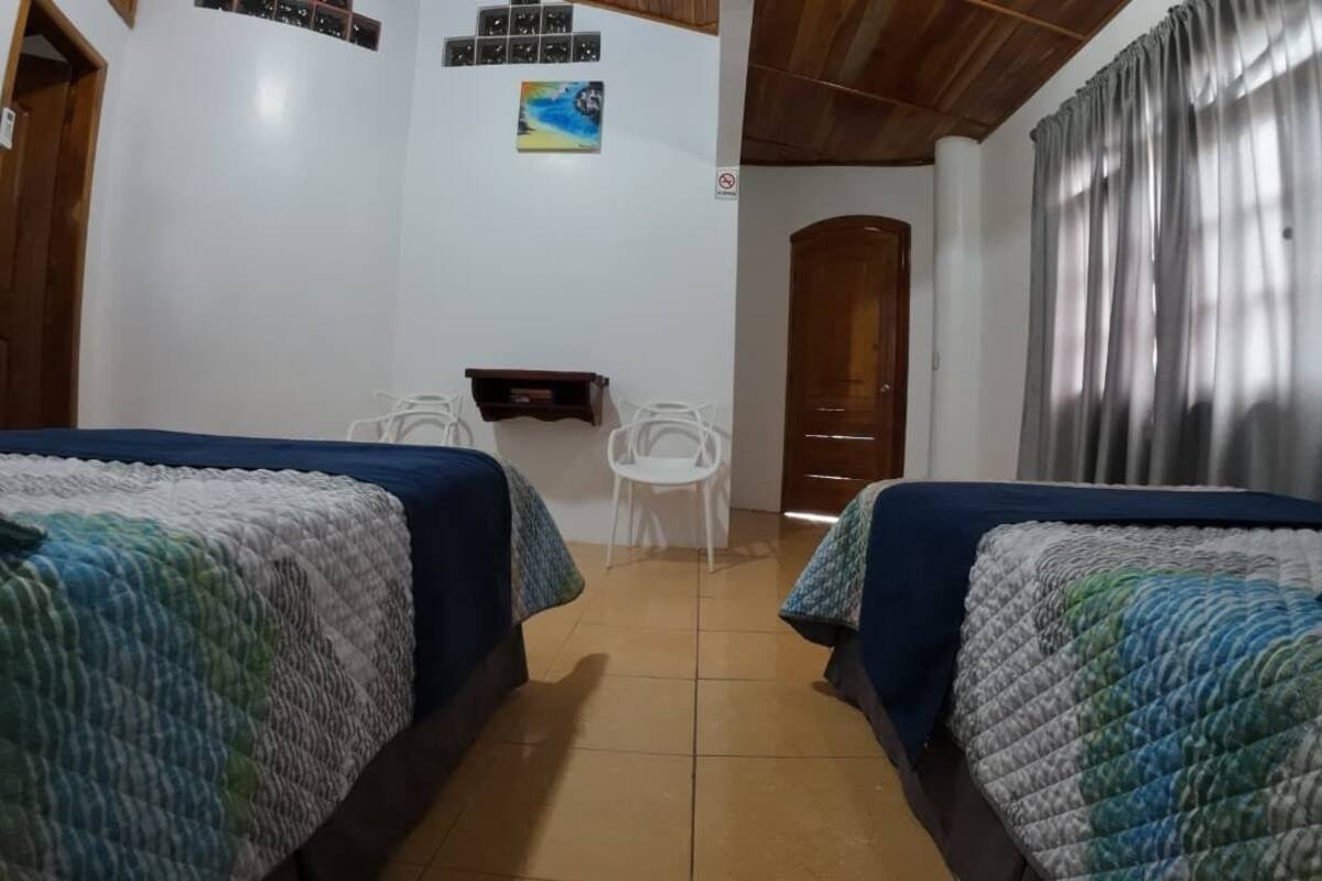 A room with two beds, a small table, and a chair.