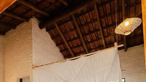 A bedroom with a four-poster canopy bed, a wooden ceiling, and a hanging light fixture. - Casa da Mata Corumbau (Prado)