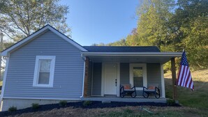 A single-story house with a porch, an American flag, and a mailbox.