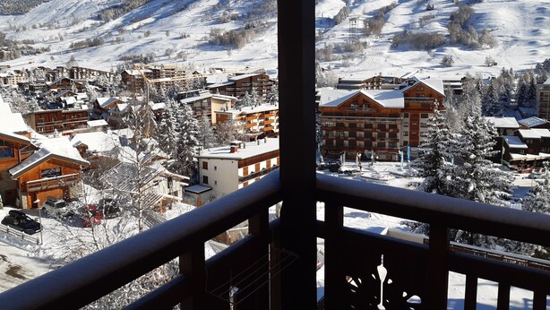A snow-covered mountain town with wooden buildings and a ski slope in the background. - Studio Cosy Les Deux Alpes Centre (Les Deux Alpes)