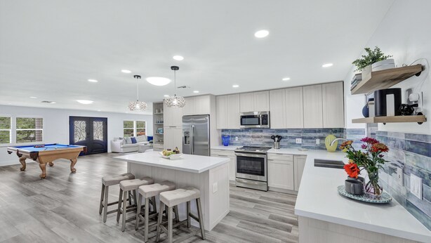 A modern kitchen with a pool table, bar stools, and a large island. - Spacious beach home - Sleeps 12 - Steps from dining, with a private heated pool (Marco Island)