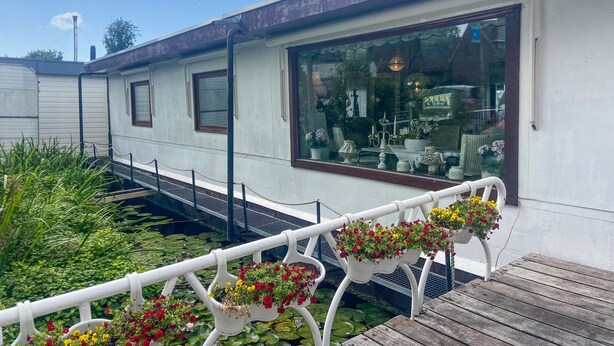 Un bâtiment blanc doté de grandes fenêtres et d’une terrasse en bois.