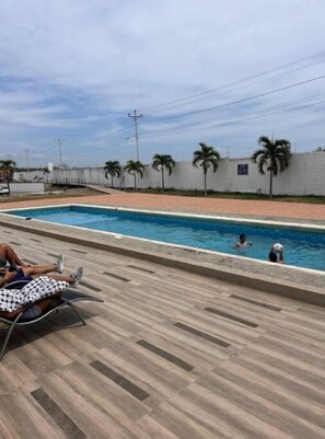 Relax by the pool surrounded by palm trees and lounge chairs.