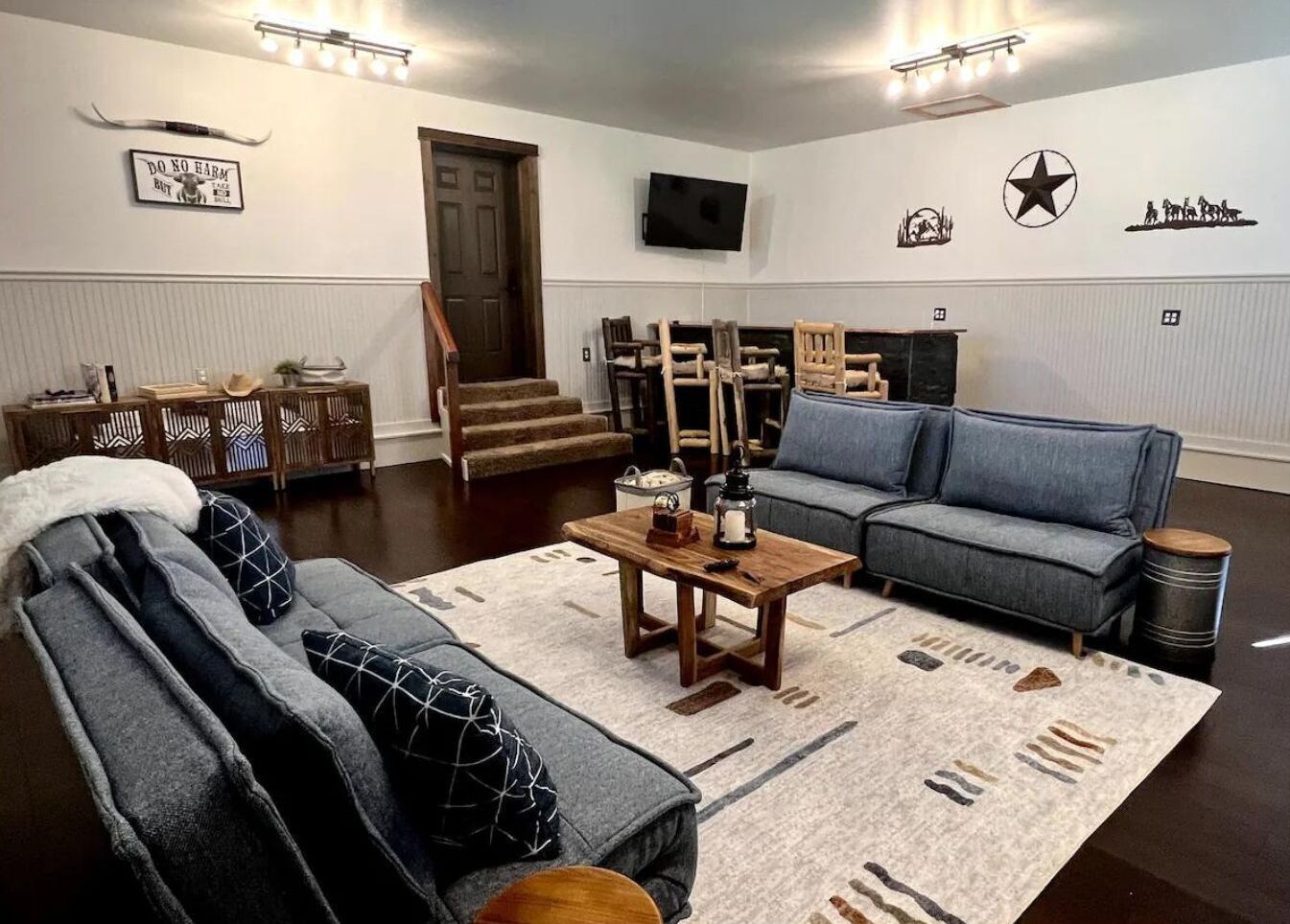 Un salon avec un canapé, une table basse et un téléviseur fixé au mur.