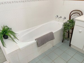 A bathroom with a bathtub, a towel, a potted plant, and a wooden chair. - Tranquil Holiday house in Kevington (Kevington)