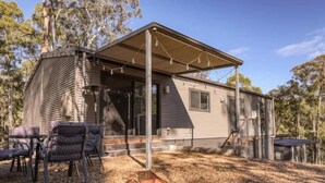 Einbungalow mit überdachter Veranda, Sitzgelegenheiten im Freien und einem Feuerkorb.