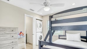 A bedroom with a bunk bed, a washing machine, a drying rack, and a ceiling fan.