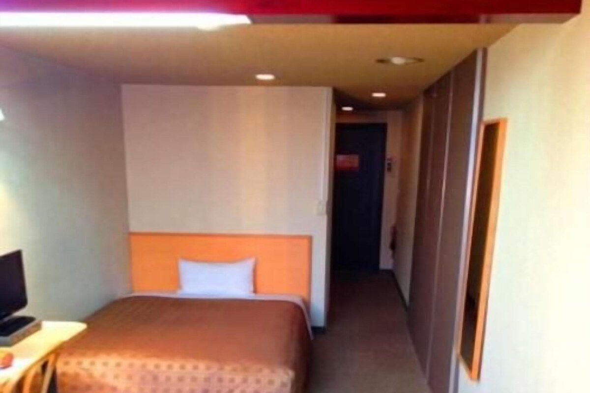 A hotel room with a bed, a desk, and a chair.