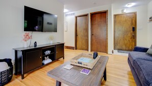 Un salon comprenant un téléviseur à écran plat, un meuble en bois foncé, une table basse avec un plateau et un canapé.