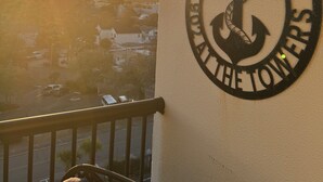Un balcón con vistas al atardecer, un letrero en la pared con un símbolo de ancla y una barandilla.