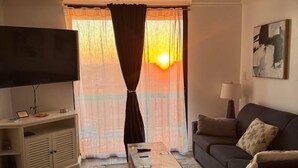 Una sala de estar con televisor, sofá y mesa de centro.