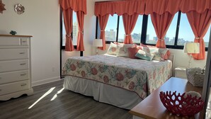 Un dormitorio con cama, cómoda, mesitas de noche y vistas a la ciudad.
