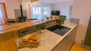 A modern kitchen with a wooden countertop, a built-in stove, a flat-screen TV, and a large window. - Eigionfa -  an on the beach that sleeps 8 guests  in 3 bedrooms (Menai Bridge)