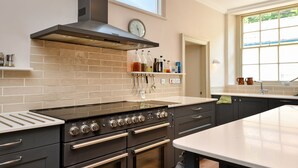 Een moderne keuken met een roestvrijstalen afzuigkap, een inbouwoven en een groot raam voor natuurlijk licht.