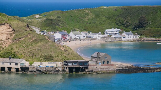 Un pueblo costero con playa, casas y un muelle.