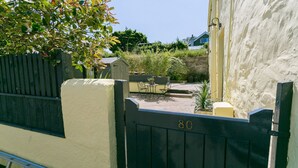 A gated entrance with a number '80' on the gate, a small patio area with a table and chairs, and a garden with various plants. - Ty Melyn -  sleeps 4 guests  in 2 bedrooms (Beaumaris)