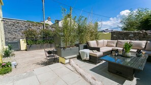 En patio med sofaarrangement, et bord med glasplade og krukkeplanter.