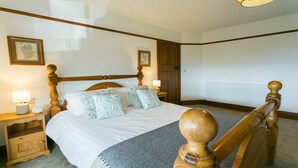 A neatly made bed with a wooden headboard, two bedside tables with lamps, and framed pictures on the wall.