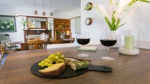 A dining table with a cheese platter, grapes, and wine glasses.