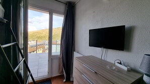 A modern room with a large sliding glass door leading to a balcony, a flat-screen TV mounted on the wall, and a wooden desk with a power strip. - 604 SKY- estudi 3 pers-balco-10 m piste- Pas de la Casa- 005778 (Pas de la Casa)