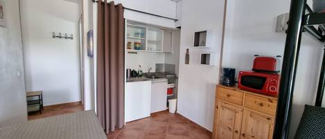 A compact kitchen with a microwave, coffee maker, and cabinets.