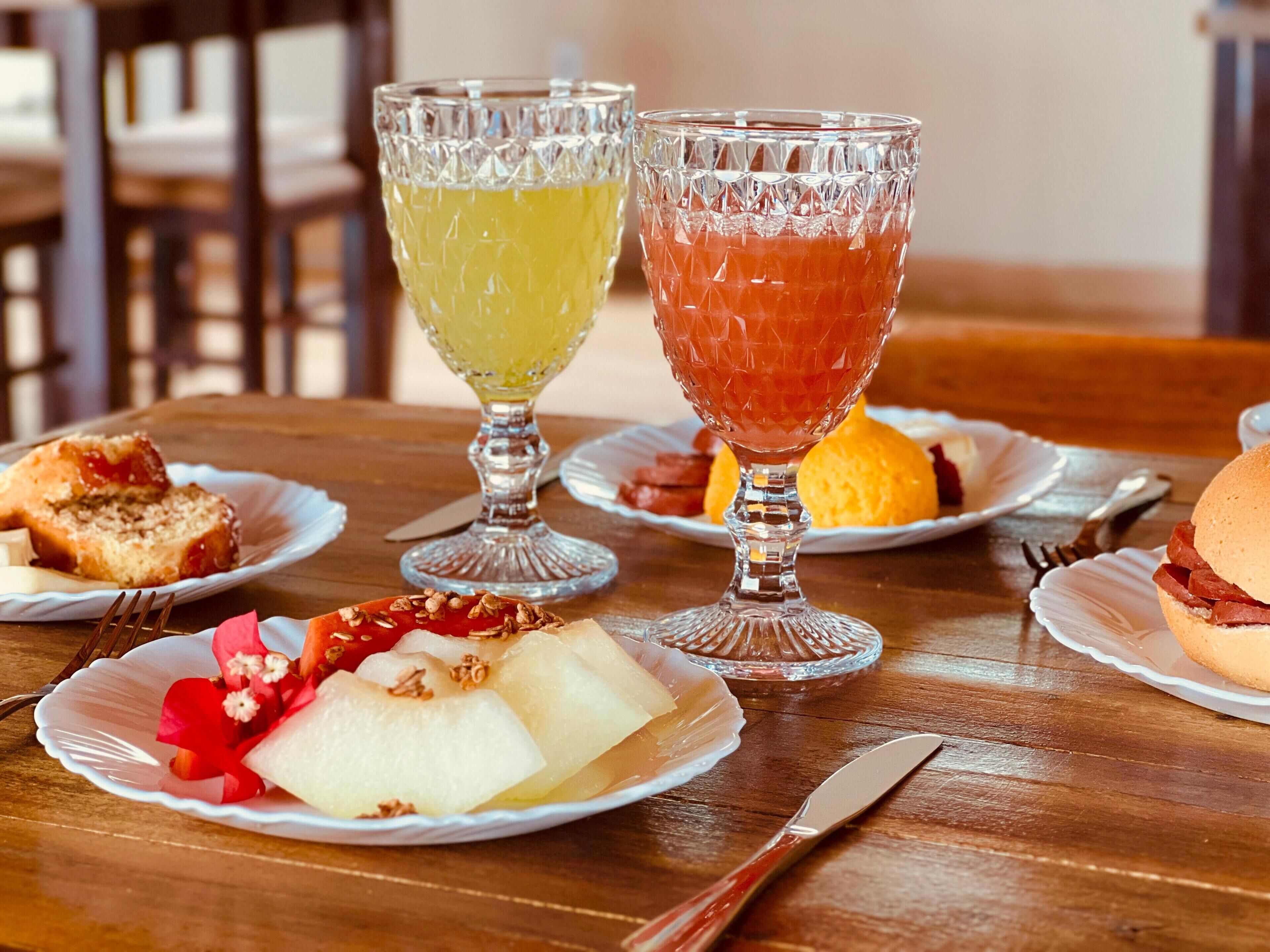 Una mesa de madera con platos de comida, dos bebidas en vasos y cubiertos.
