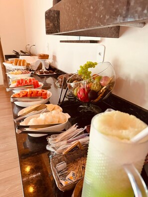 Una barra de buffet con diferentes tipos de comida y una jarra de bebida verde.