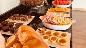 Una mesa de buffet con diversos alimentos, incluyendo pasteles, frutas y sándwiches.