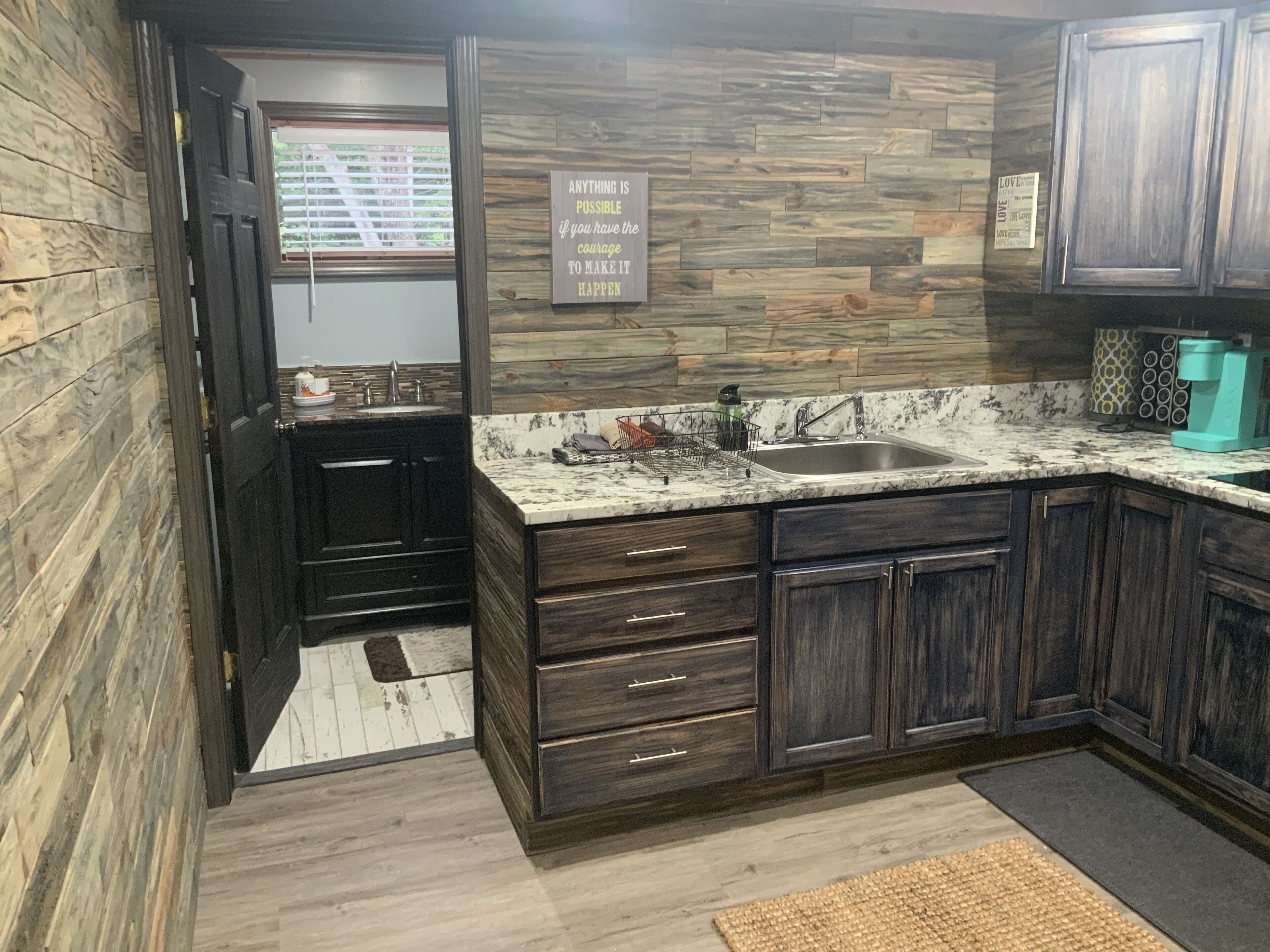 A kitchen with dark wooden cabinets, a granite countertop, and a stone backsplash.