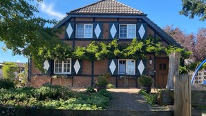 Een huis met twee verdiepingen, een bakstenen gevel, shutters in een ruitpatroon en een pannendak.