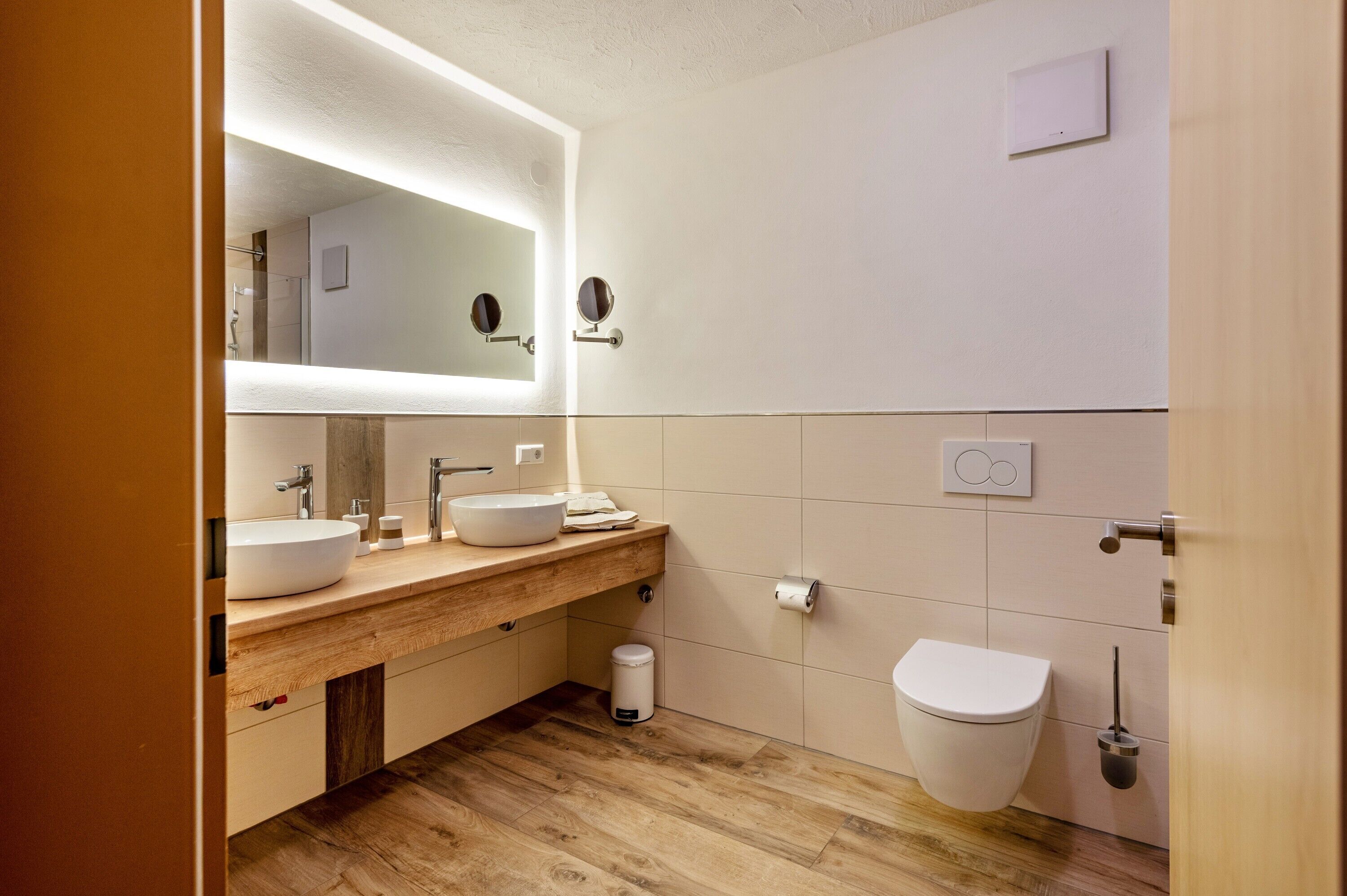Een moderne badkamer met een grote spiegel, een wastafel, een toilet en een bidet.