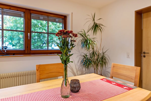 A dining table with a checkered tablecloth, a vase with flowers, and chairs.