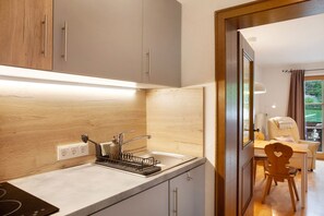 Una cocina moderna con estufa integrada, un lavamanos con escurreplatos y armarios de madera.