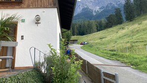 Ein Holzgebäude mit weißer Fassade, einer Treppe und Blick auf Berge.