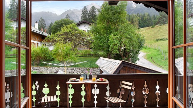 Ein Balkon mit Tisch, Stühlen und Blick auf eine Berglandschaft.