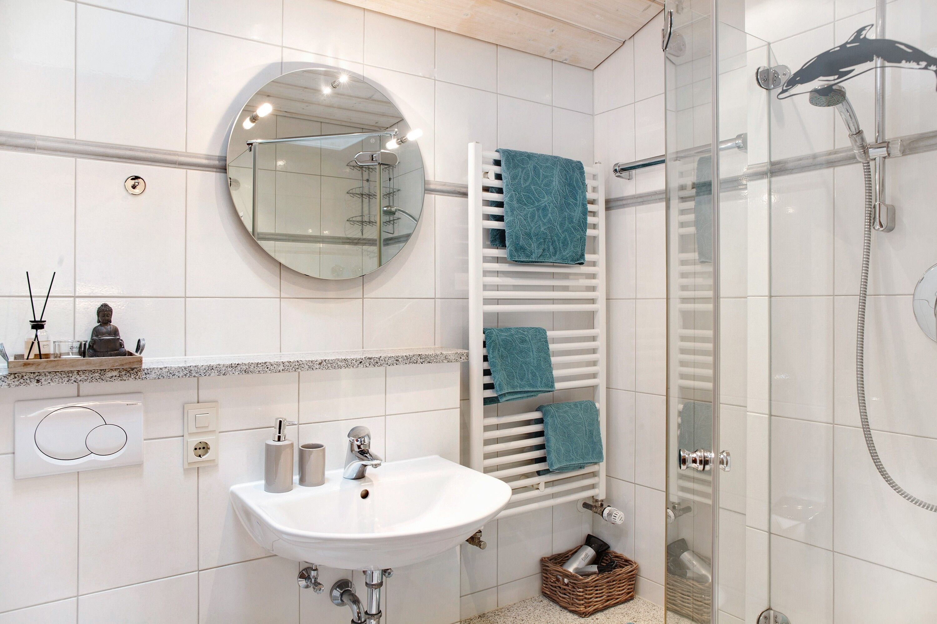 Un baño con lavamanos, espejo, toallero, ducha y cabina de ducha acristalada.