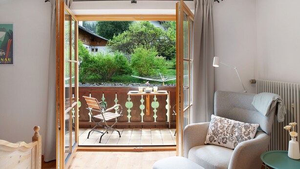 Una habitación con balcón, una silla, una mesa y un radiador.